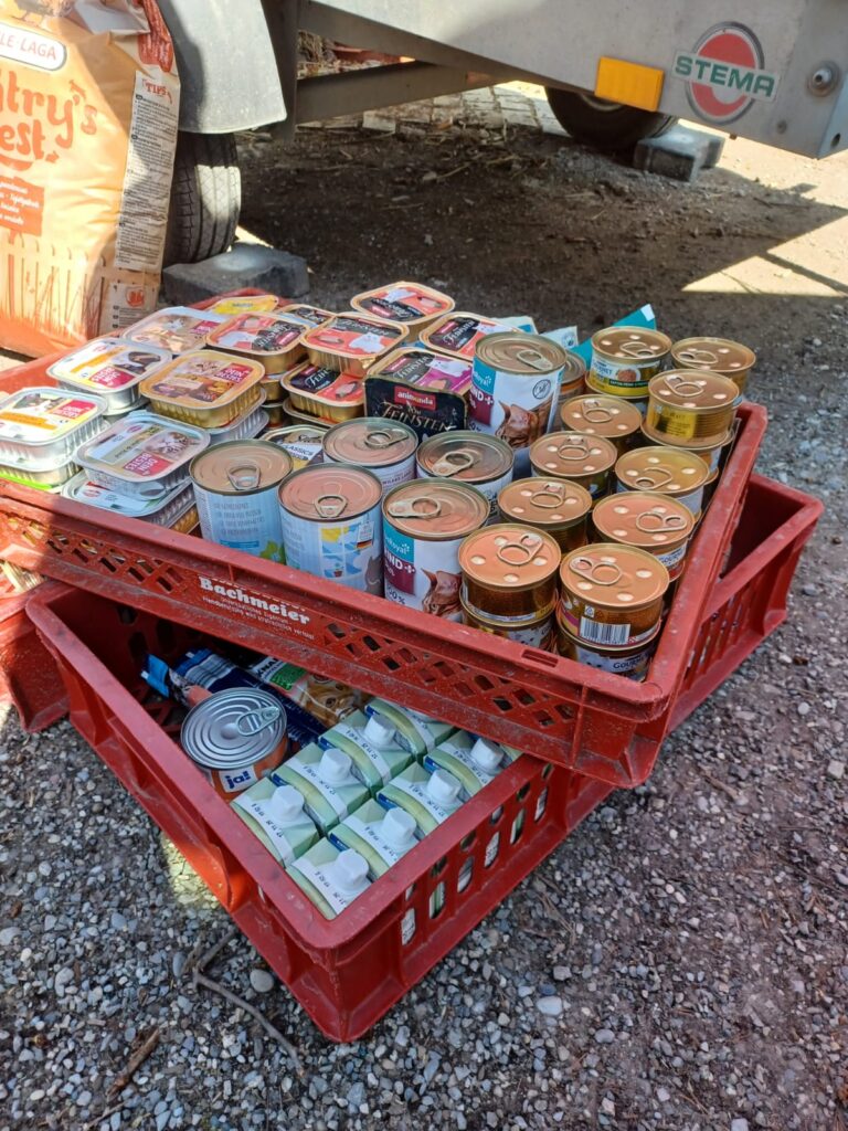 Zwei rote Kisten mit Lebensmitteln und Futterdosen stehen auf dem Boden.